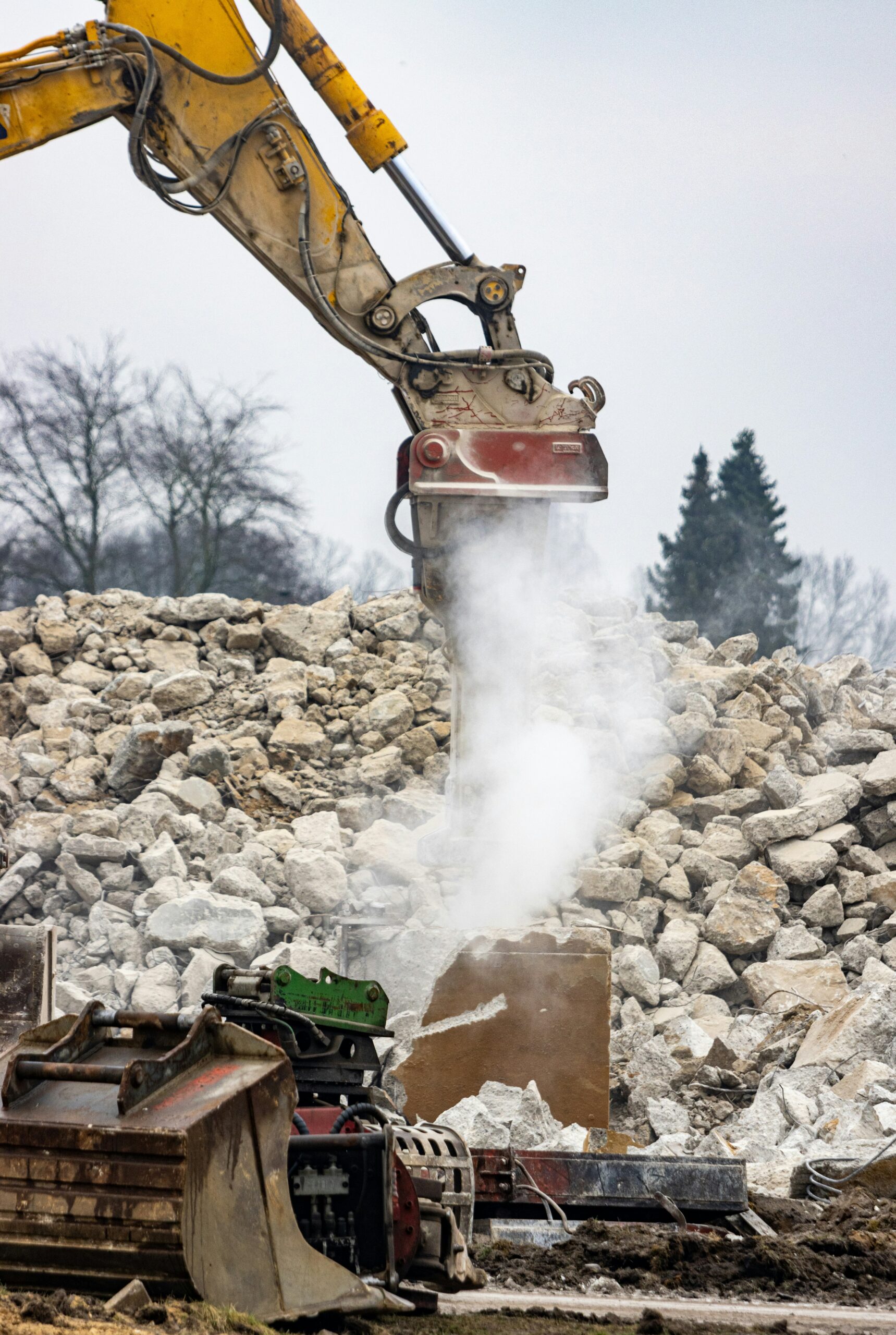 a construction site with a large excavator and a pile of rubble