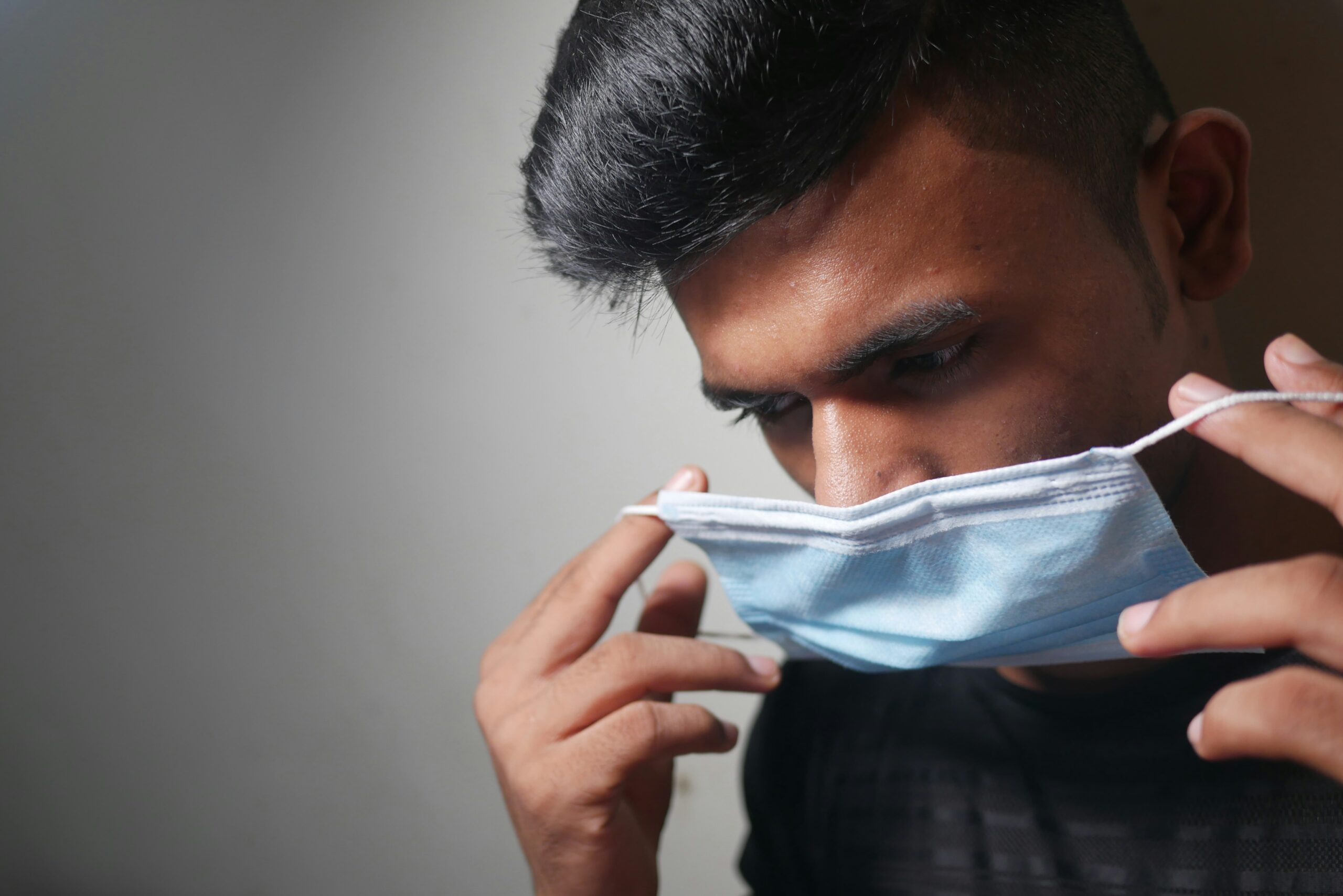 man in black shirt covering his face with white textile